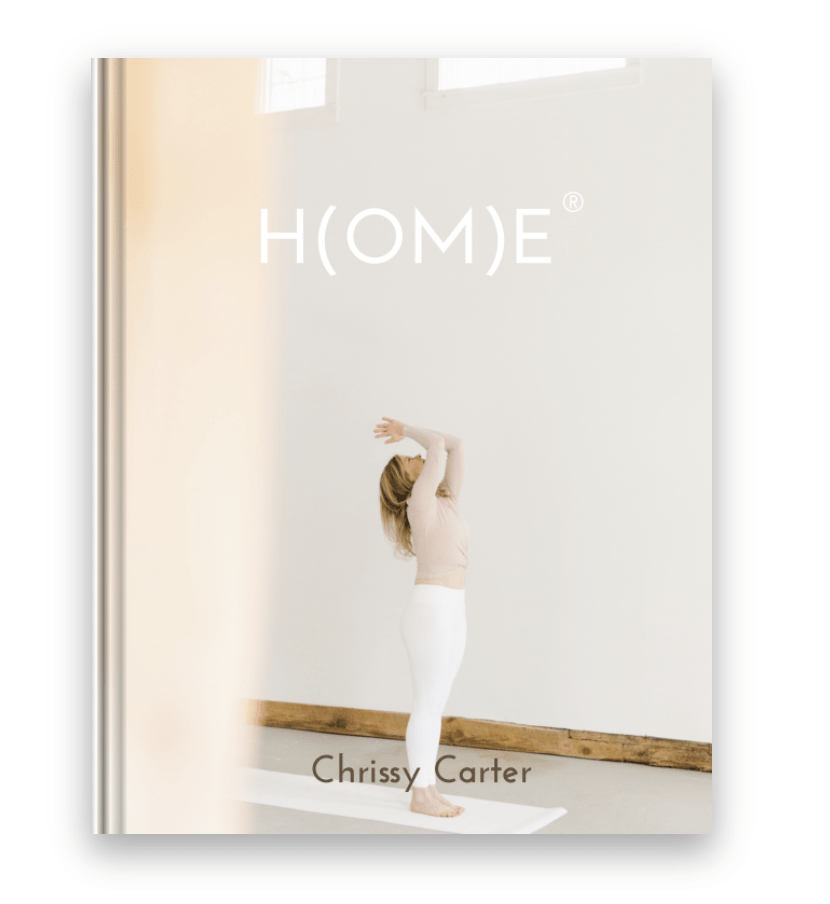 H(OM)E® Book by Chrissy Carter with Chrissy in yoga pose on white mat